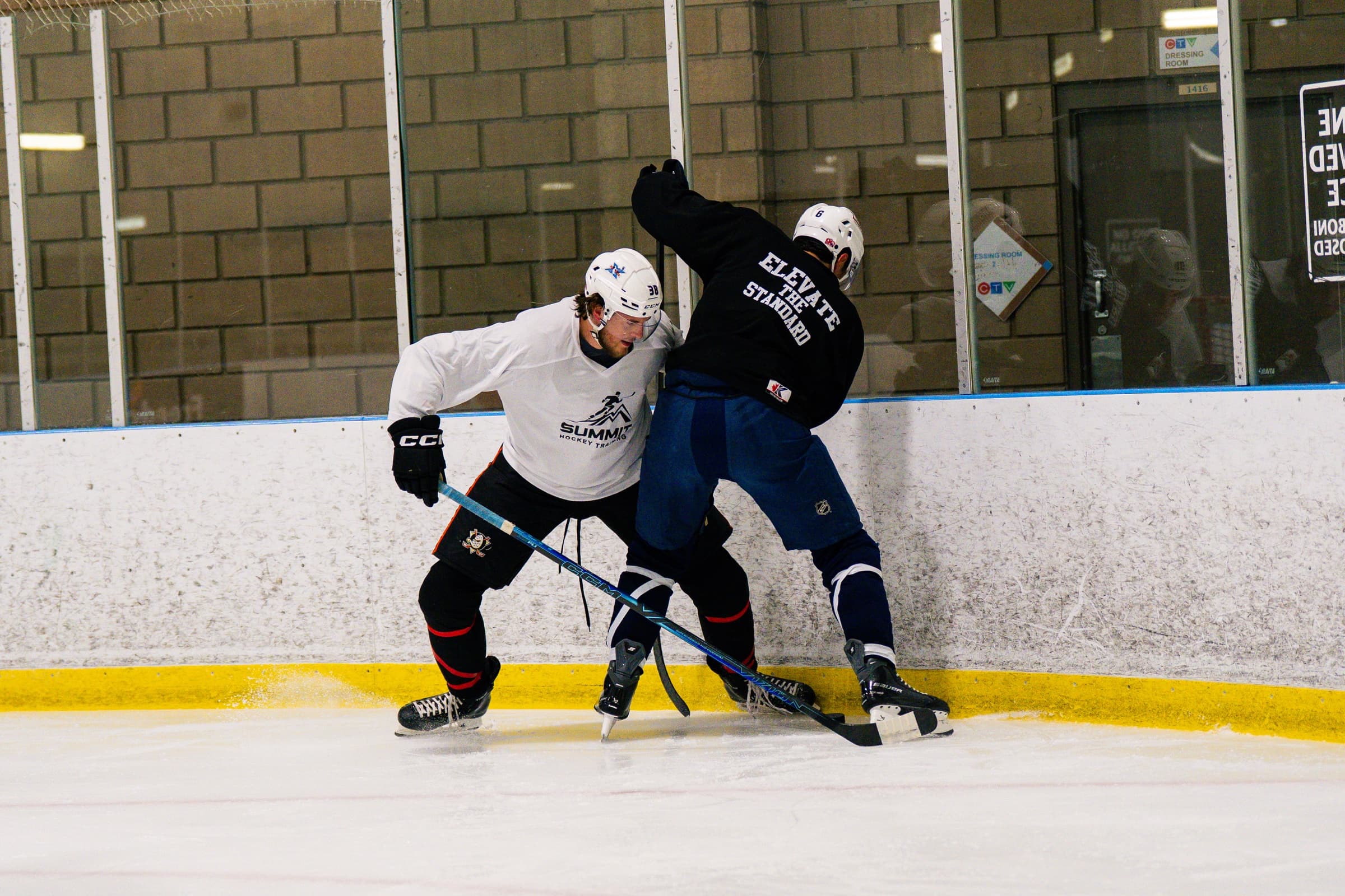 Two players battling for position along the boards during defence training