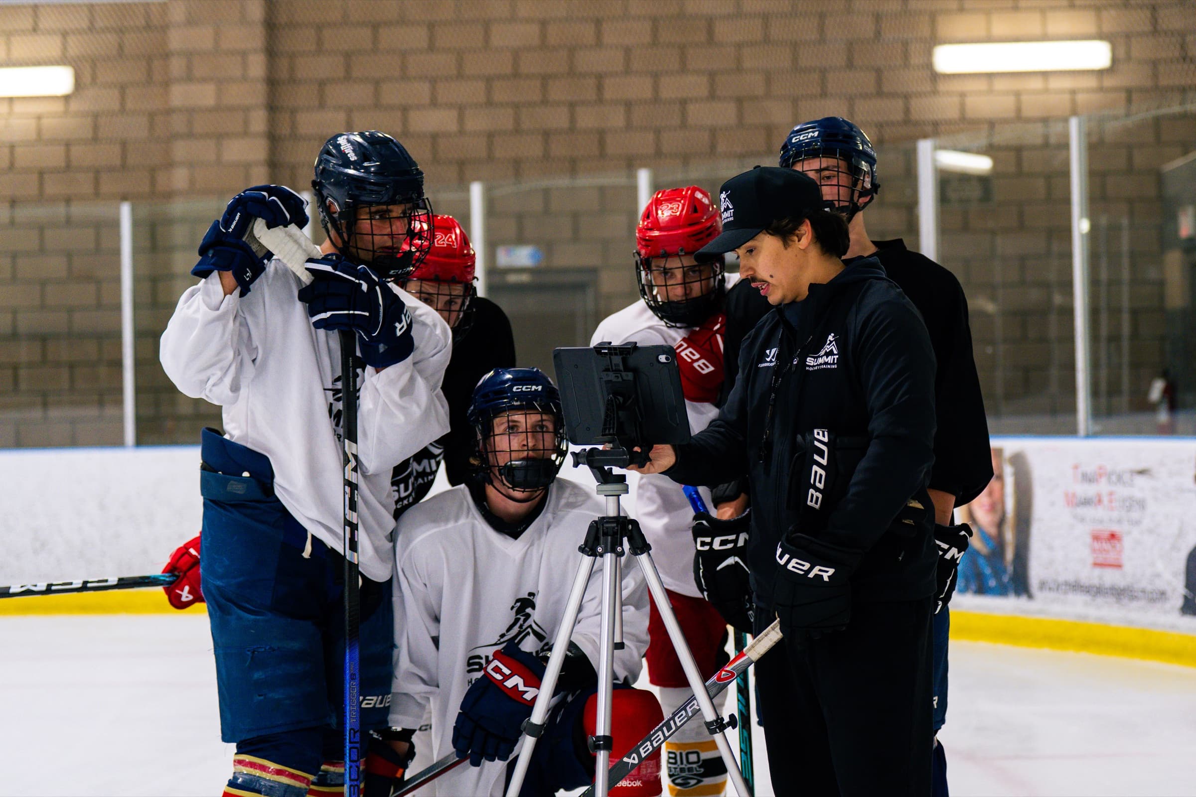 A coach and players reviewing game film together on a tablet