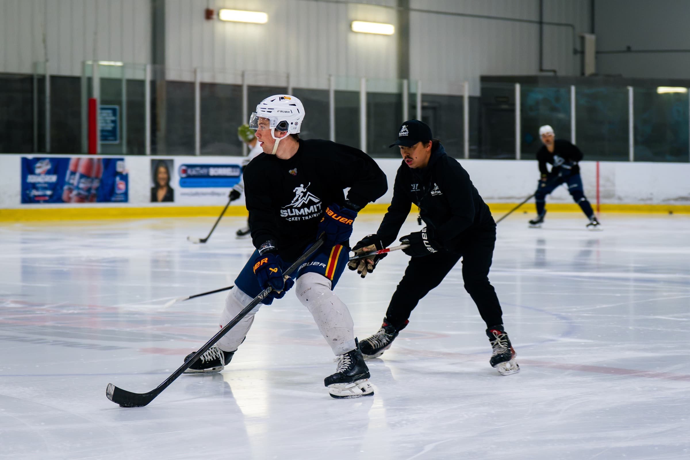 A player working through an on-ice skill drill with a coach