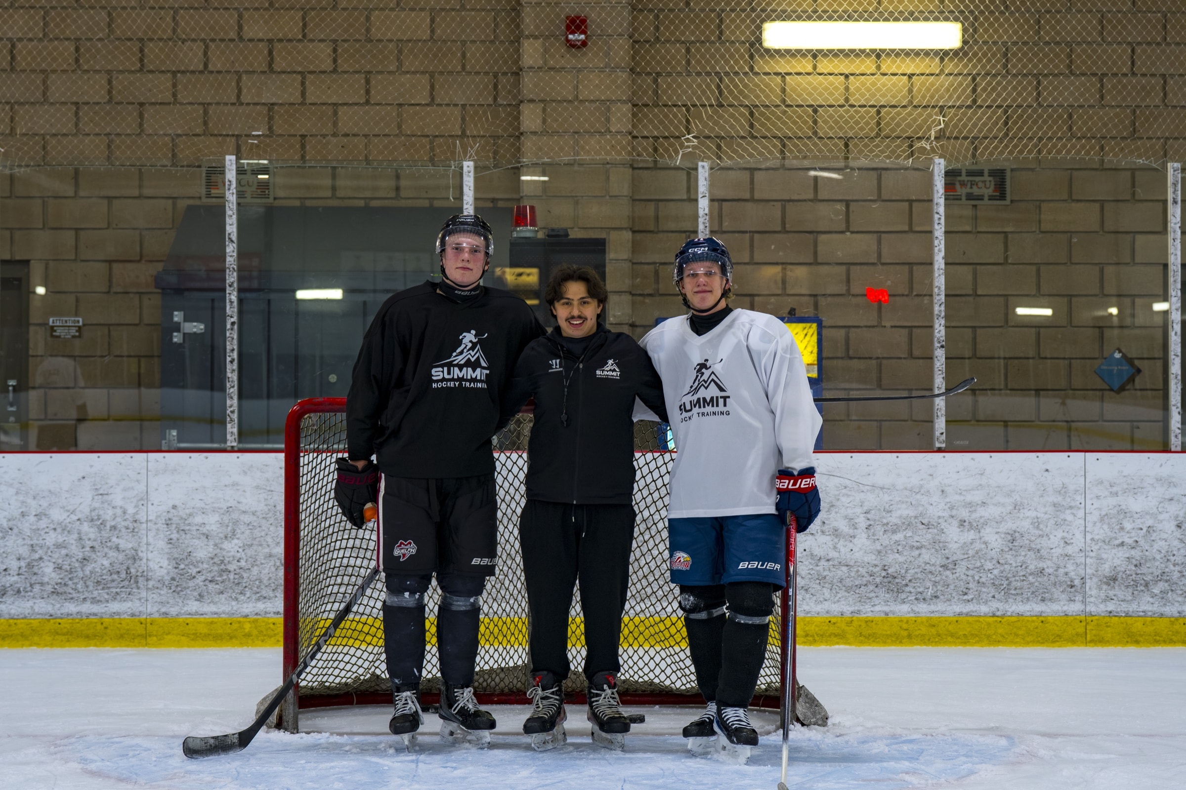 Summit Hockey coach standing on the ice with two players