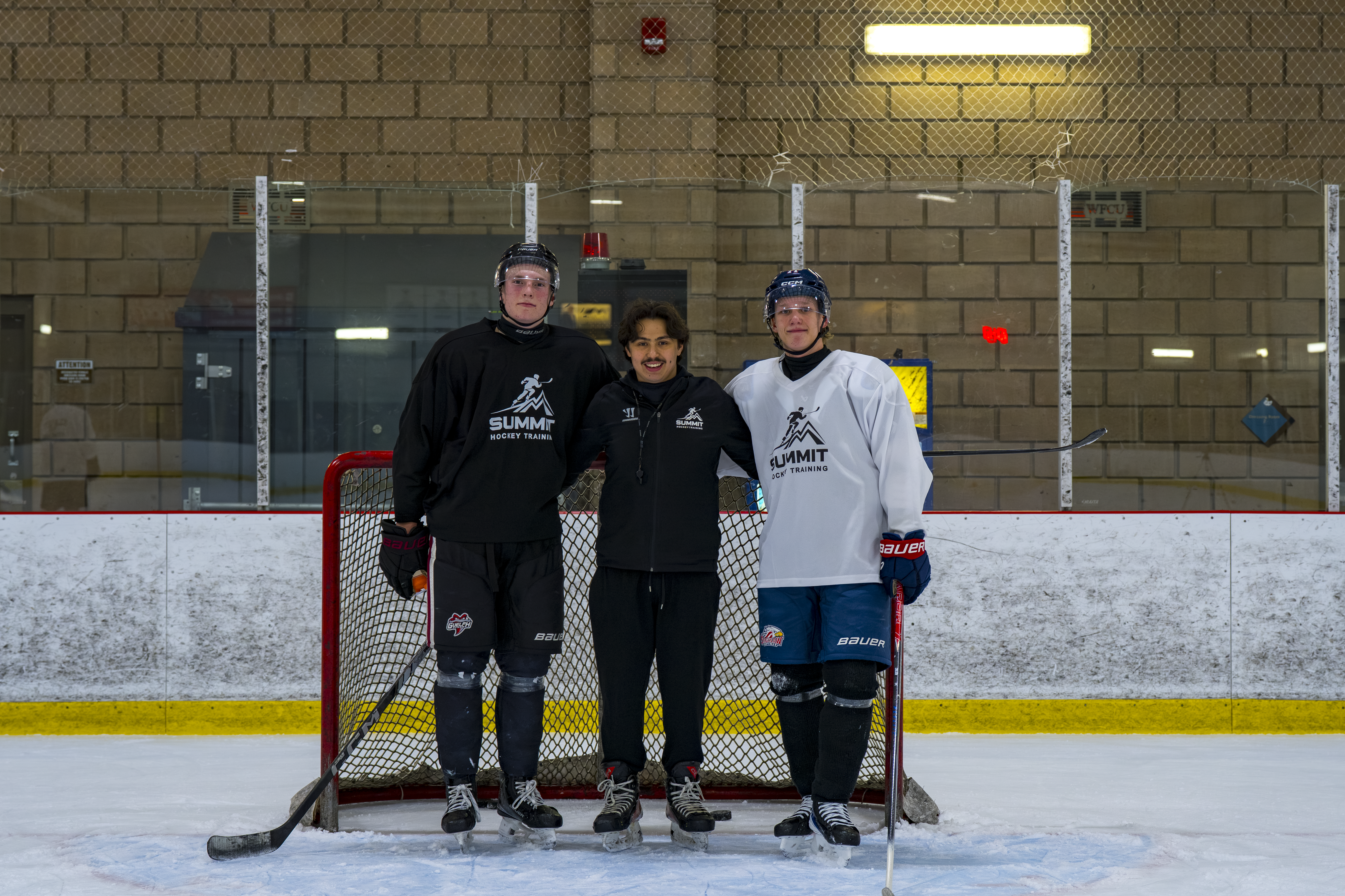 Summit Hockey coach standing on the ice with two players